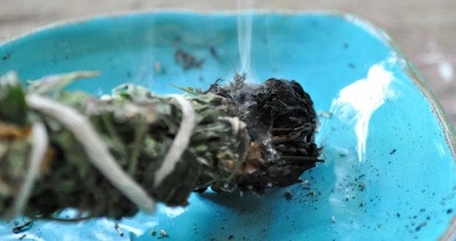 Burning an herb bundle to smoke cleanse.