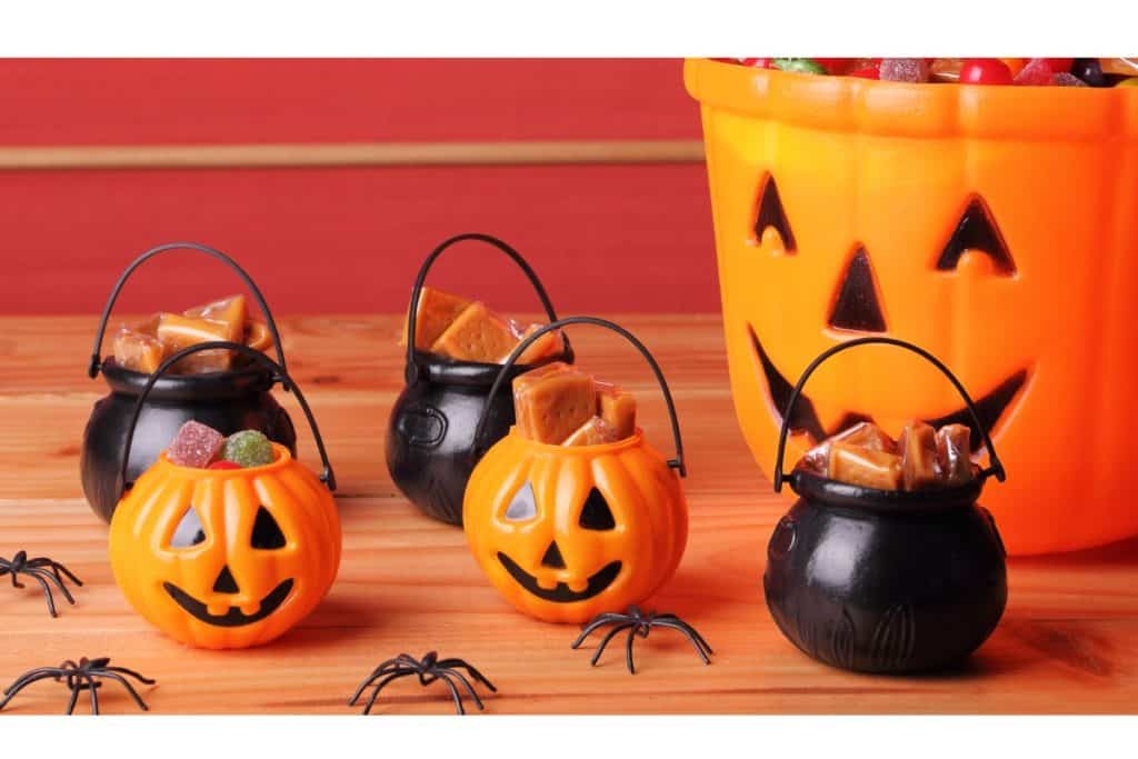 Mini buckets of Halloween candy with spiders and a jack-o'-lantern.