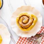 Pumpkin cinnamon roll on a plate with red and white ginham.