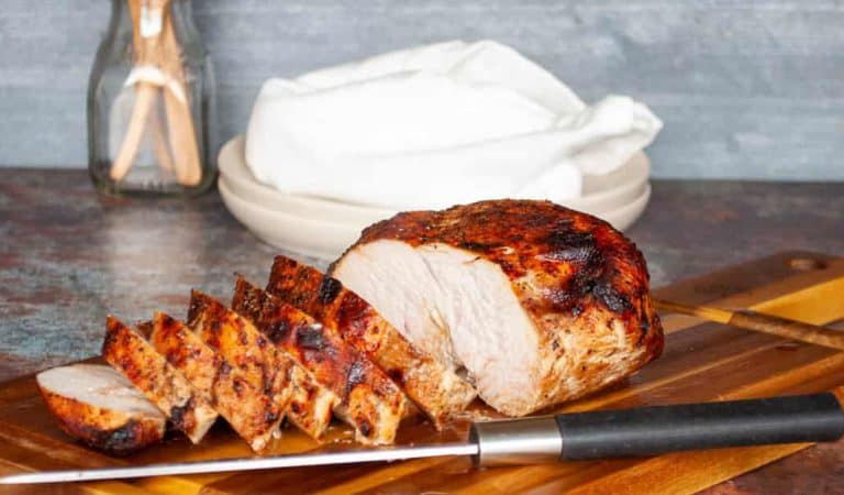 Sliced air fryer turkey breast with a golden, crispy exterior on a cutting board.