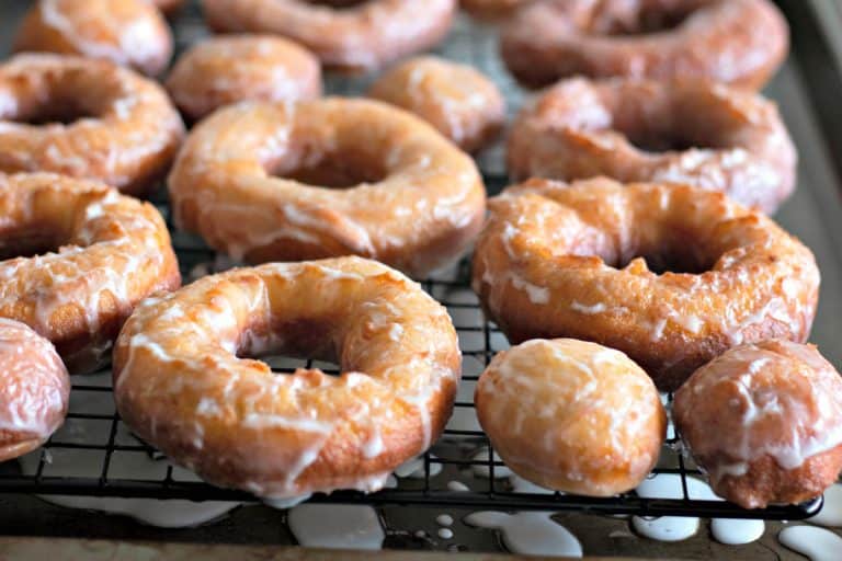 Freshly glazed Amish Doughnuts on a wire rack.
