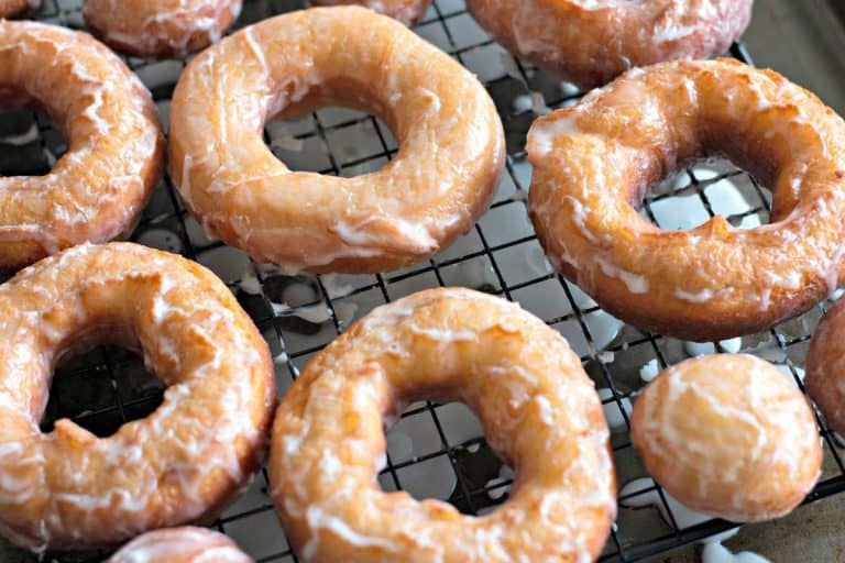 Freshly glazed Amish Doughnuts on a wire rack.
