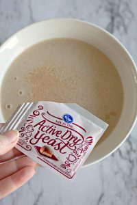 A packet of active dry yeast held over a bowl.