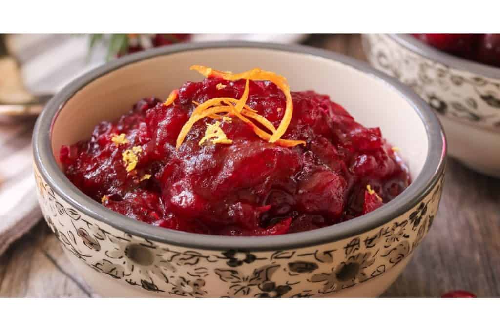 Cranberry jelly in a bowl with orange peel. 