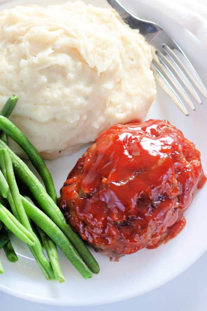 Mini meatloaf with sauce, served with green beans and mashed potatoes.