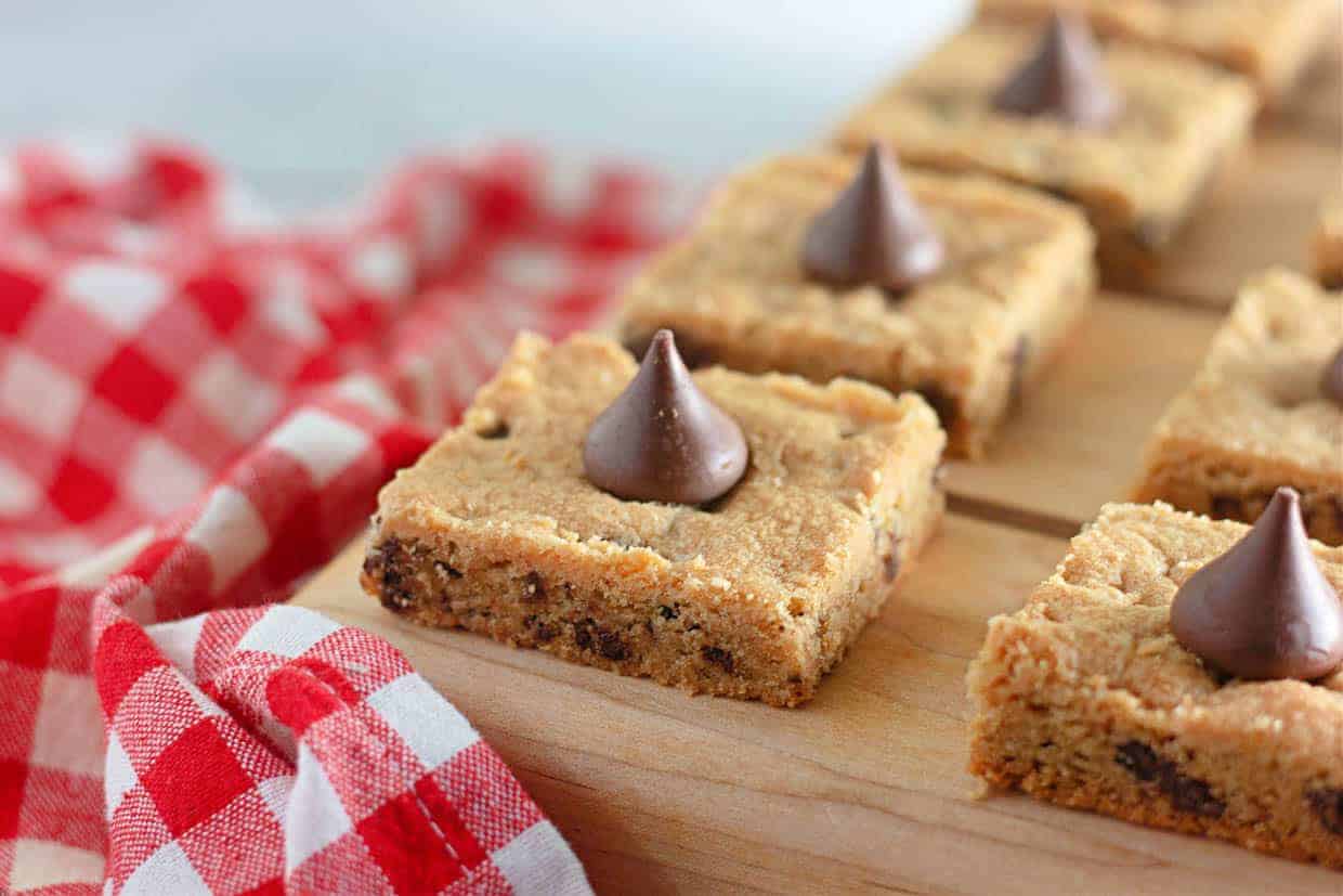 Chocolate chip cookie bars on a wooden cutting board.