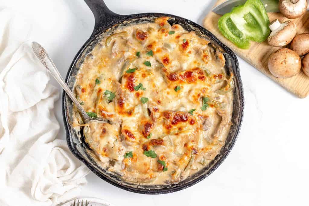 Philly cheesesteak casserole with melted cheese in a cast-iron skillet.