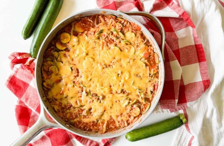 Unstuffed zucchini casserole topped with melted cheese in a skillet.