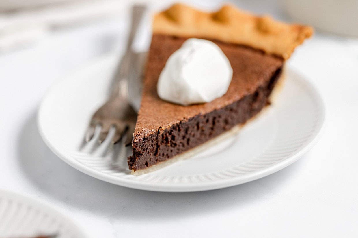 A slice of chocolate chess pie with a fork next to it.
