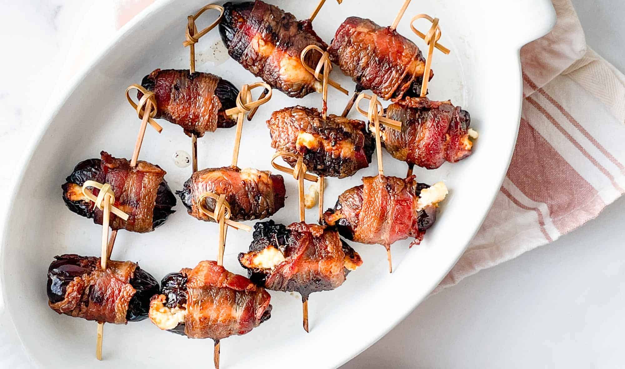 Bacon wrapped around dates and goat cheese in a dish. 