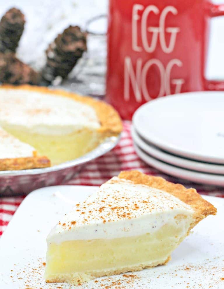 Eggnog pie on a plate with a cup behind it.