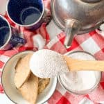 Kettle, Russian tea mix, and cookies on a red-and-white checkered cloth.