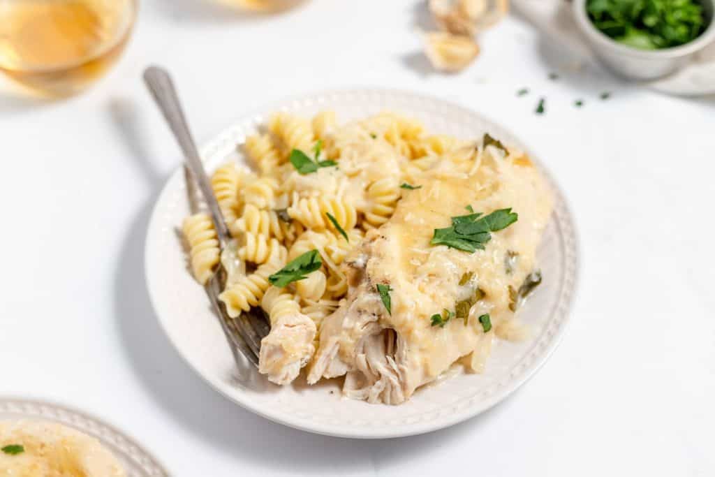 Slow cooker garlic parmesan chicken served with rotini pasta.