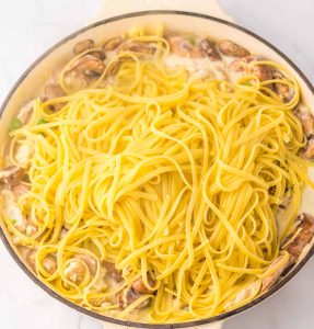 Cooked pasta and mushrooms in a skillet for turkey tetrazzini.