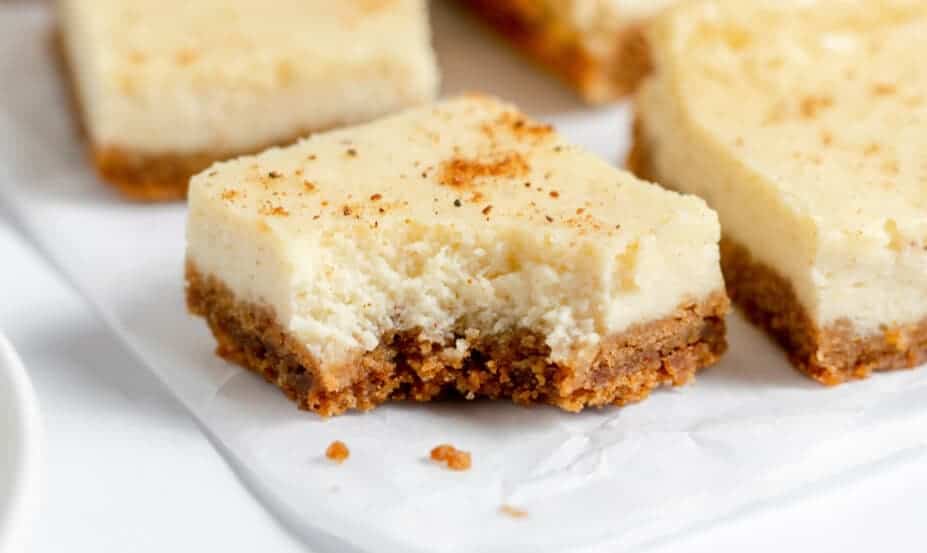 Eggnog Cheesecake bars one with a bite out of it. 