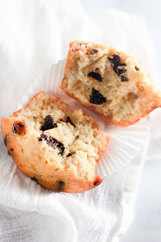 A single muffin split in half, showing the moist texture and melted chocolate chips inside.