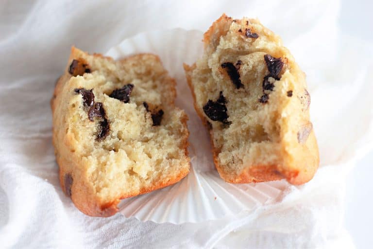 A single muffin split in half, showing the moist texture and melted chocolate chips inside.