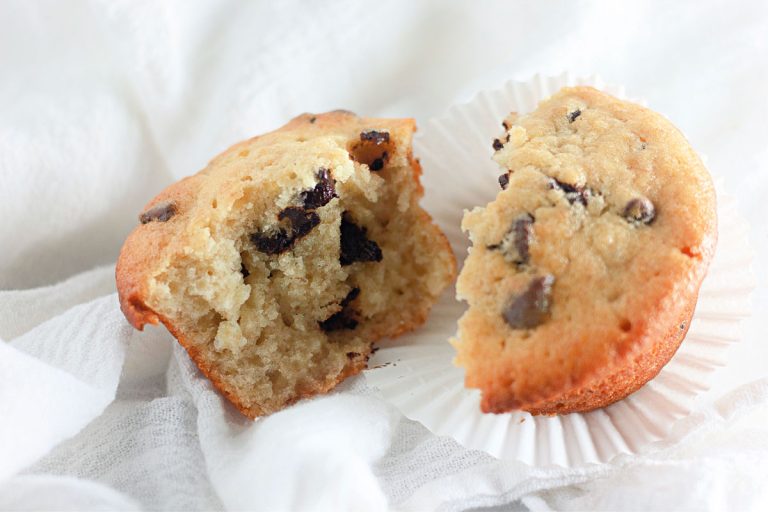 A single muffin split in half, showing the moist texture and melted chocolate chips inside.
