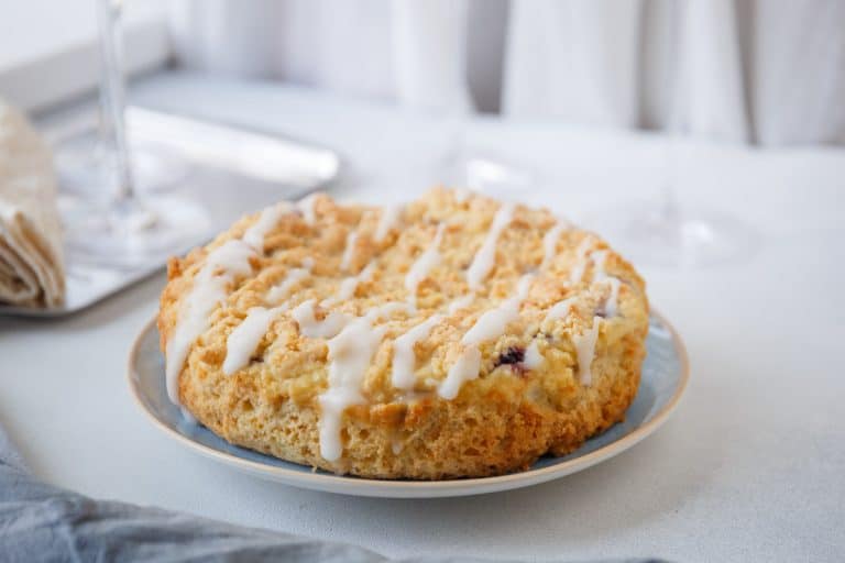 Blueberry cheesecake crumb cake plated with icing drizzle, ready to serve.