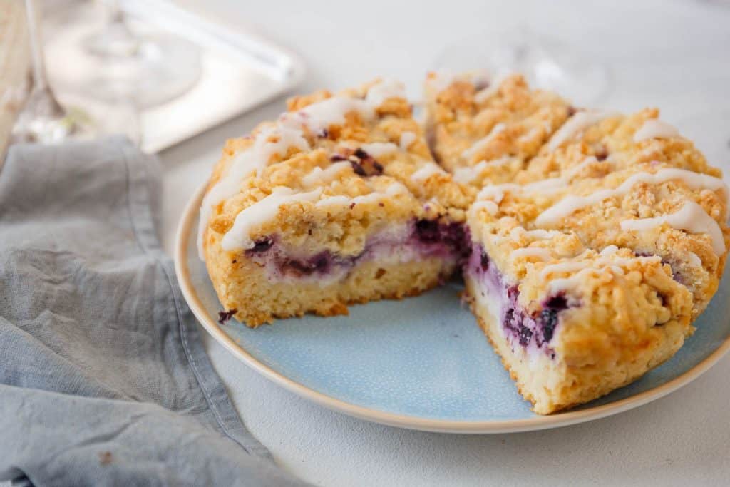 Blueberry cheesecake crumb cake sliced and served on a blue plate.