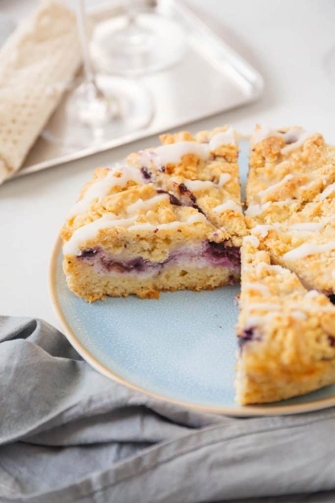 Blueberry cheesecake crumb cake sliced and served on a blue plate.