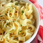 A bowl of Buttered Noodles garnished with parsley for serving.