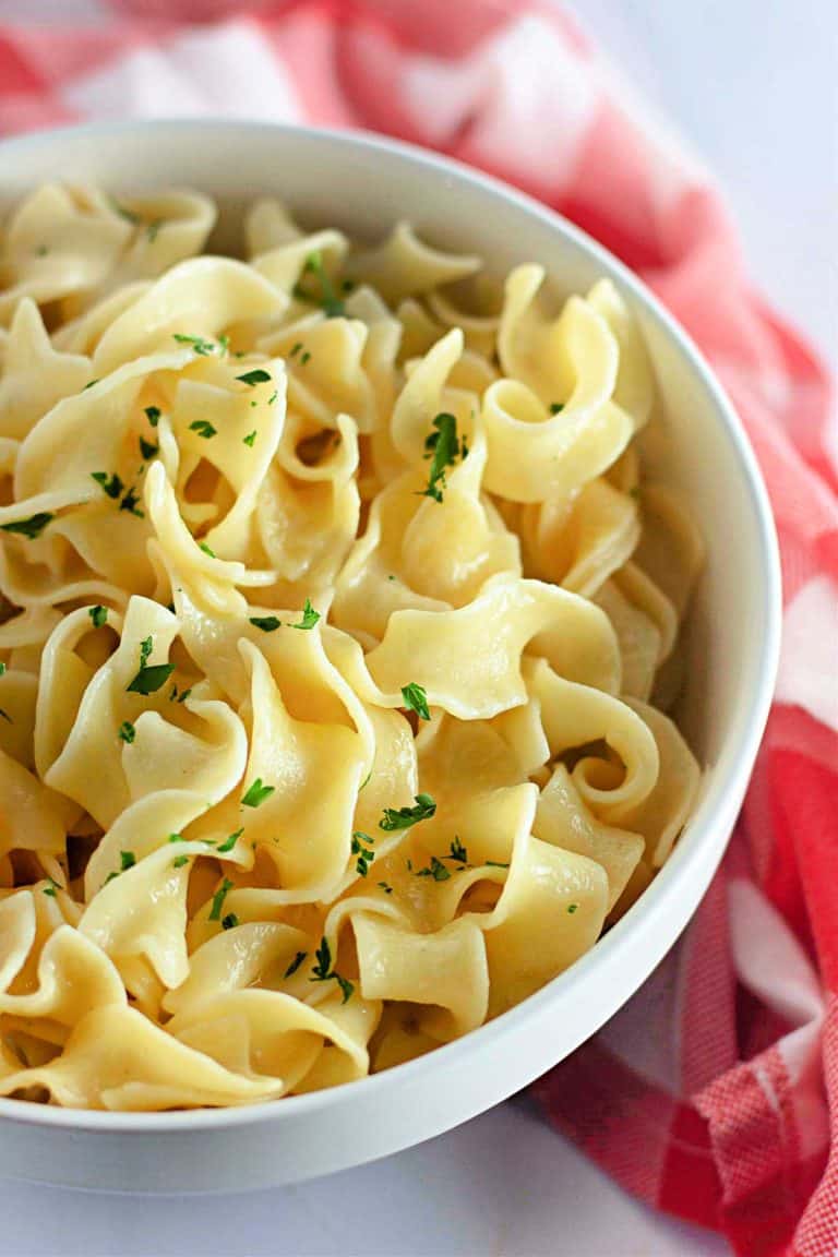 A bowl of Buttered Noodles garnished with parsley for serving.