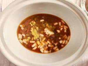 Ingredients for chicken tortilla soup in a slow cooker, including diced onions and spices.