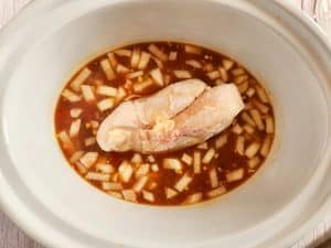 Raw chicken breasts added to the slow cooker with the soup ingredients.