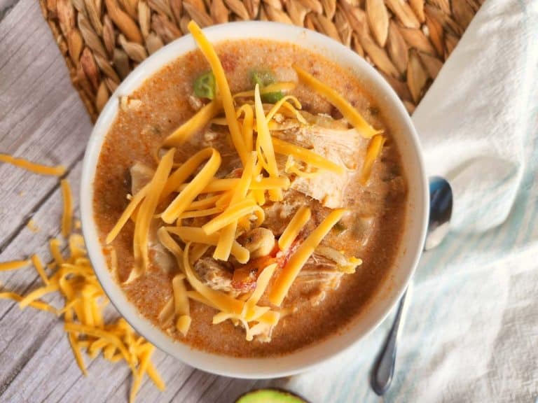 Bowl of chicken tortilla soup topped with shredded cheese.