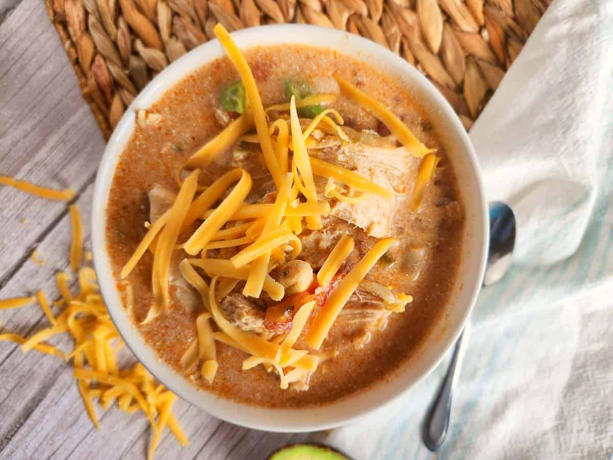Bowl of chicken tortilla soup topped with shredded cheese.