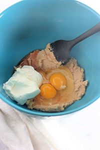 Eggs, sour cream, vanilla, and creamed sugar mixture in a blue bowl for the muffin batter of Streusel Topped Apple Muffins.