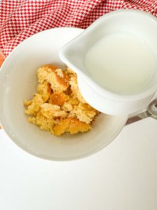 A small pitcher of milk next to the crumbled cornbread.