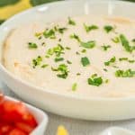 Close-up of easy taco dip with a creamy texture, garnished with cilantro and green onions.