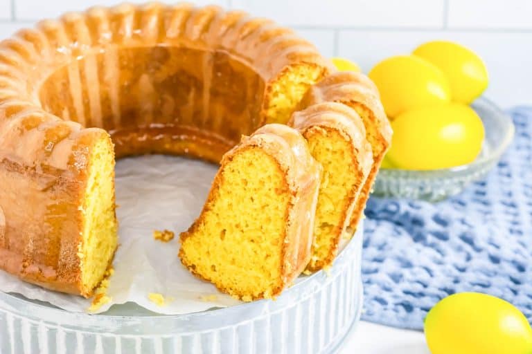 Sliced lemon pudding cake with whole lemons nearby.