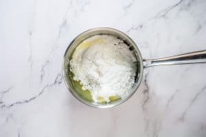 Glaze ingredients for lemon pudding cake in a saucepan.