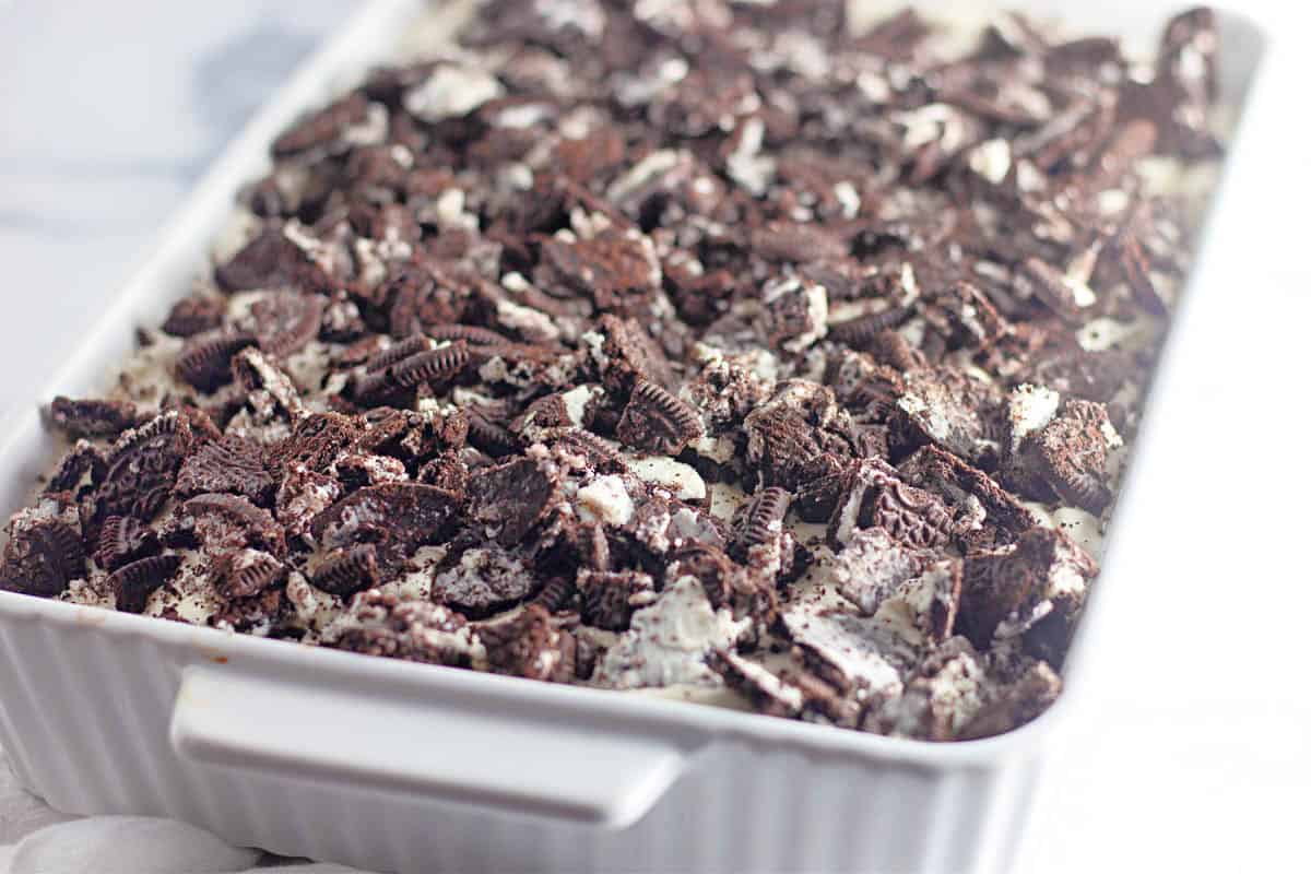 A slice of Oreo poke cake on a white plate.