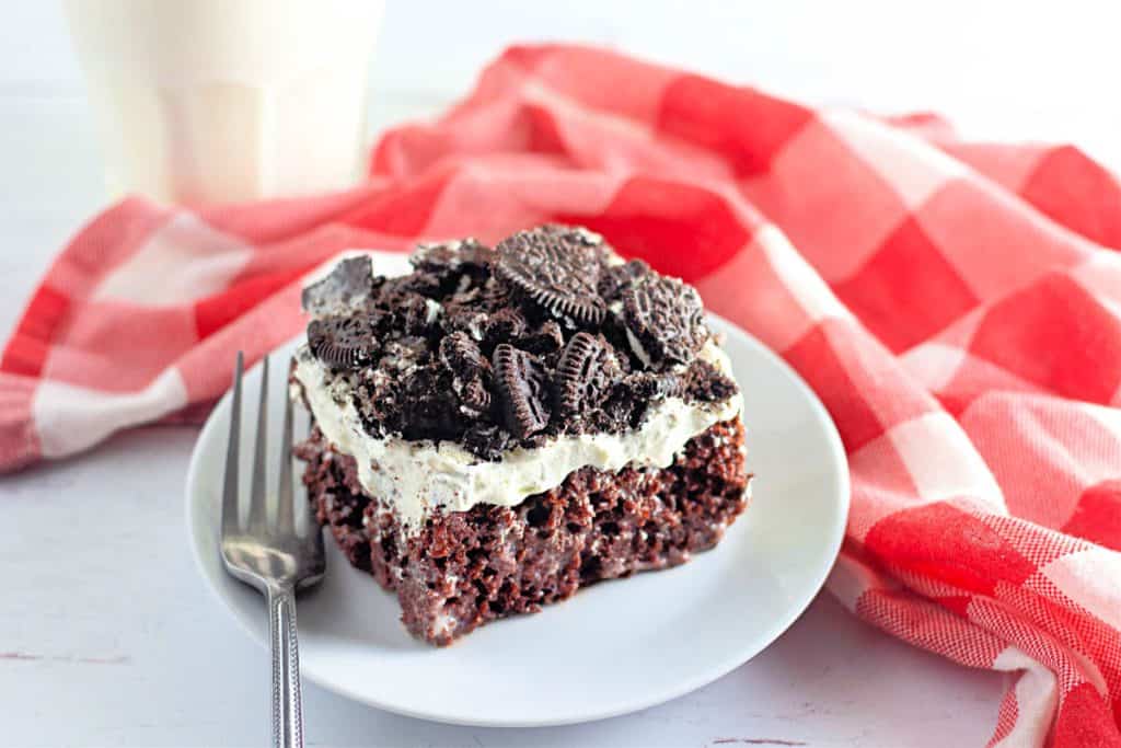 A slice of Oreo poke cake on a white plate.