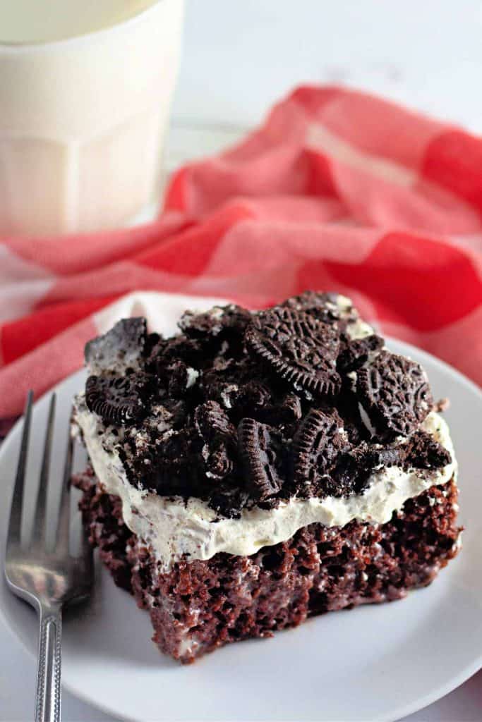 A slice of Oreo poke cake on a white plate.