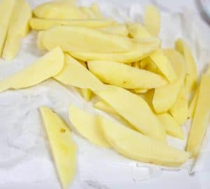 Peeled and sliced potatoes on parchment paper.