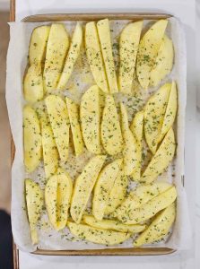 Seasoned potato wedges on a baking sheet.