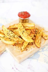 Golden-brown potato wedges with herbs.
