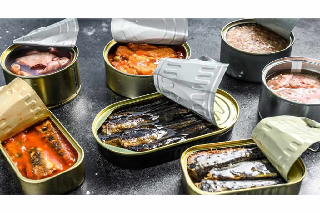 Assorted open cans of sardines and other canned seafood.