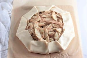 Unbaked apple galette with cinnamon-sugar apples, edges of pie crust folded over.