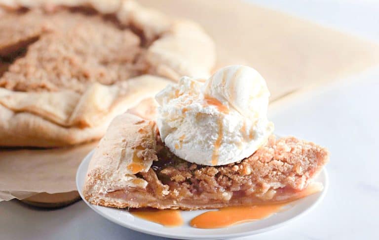 Close-up of apple galette slice topped with ice cream and caramel sauce.