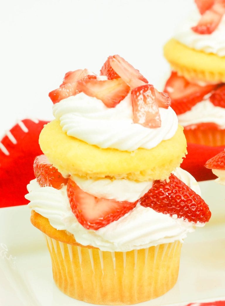Close-up of a layered strawberry shortcake cupcake with whipped cream.