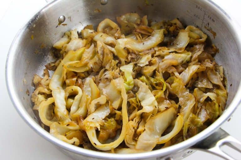 Close-up of caraway seeds and salt on top of cabbage in a pot.