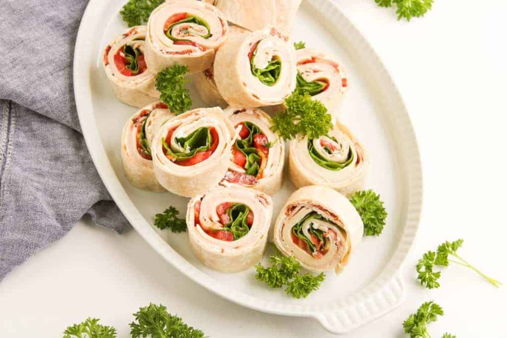 Tightly rolled turkey pinwheels with crisp lettuce and diced tomato in the center.