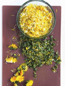 Dandelion petals separated from the greens on a cutting board.