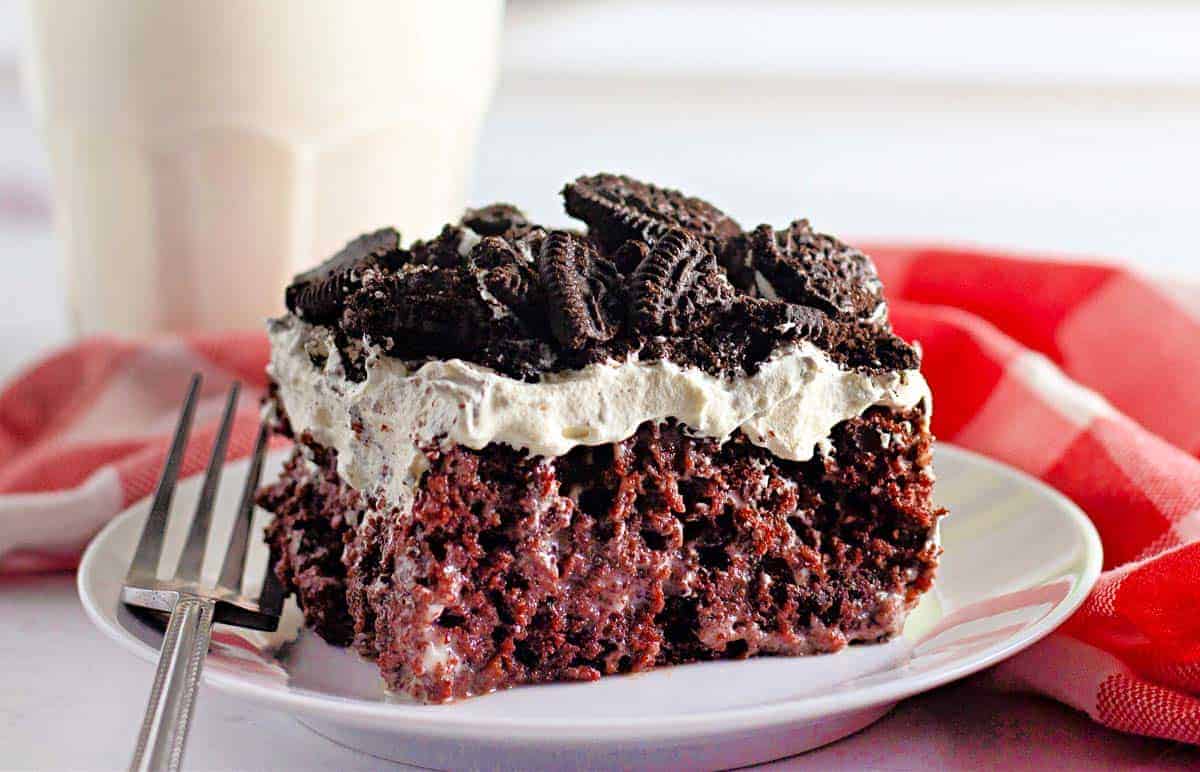 A slice of Oreo poke cake on a white plate.